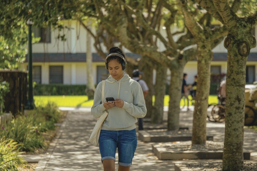 A student walks
along the sidewalk between the Banyan Dining
Hall and the McKay building.