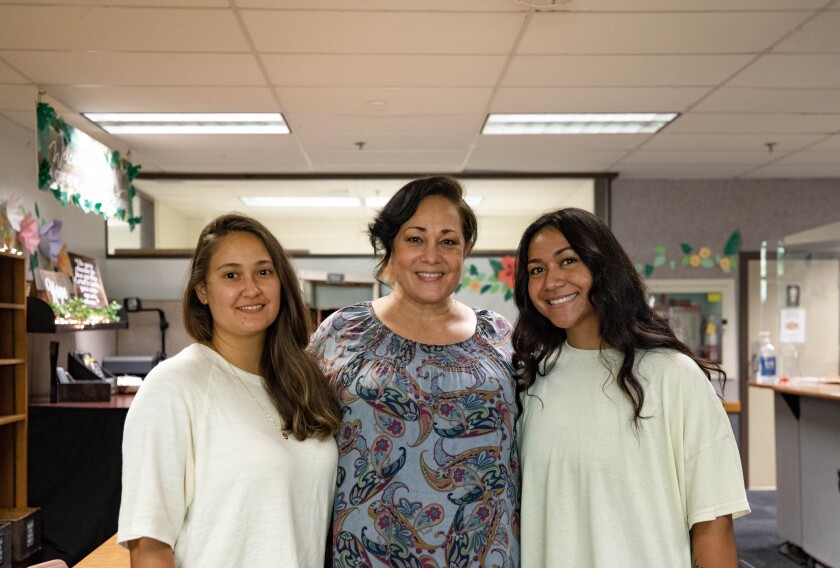 Three women smiling looking in the same direction.