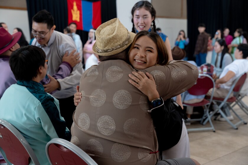 Two people hug in a crowded room.