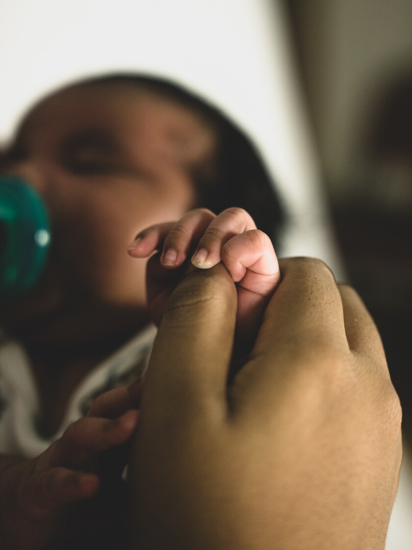 Baby holding onto mother's finger