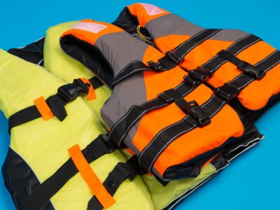 Orange life vest placed on top of a yellow green life vest