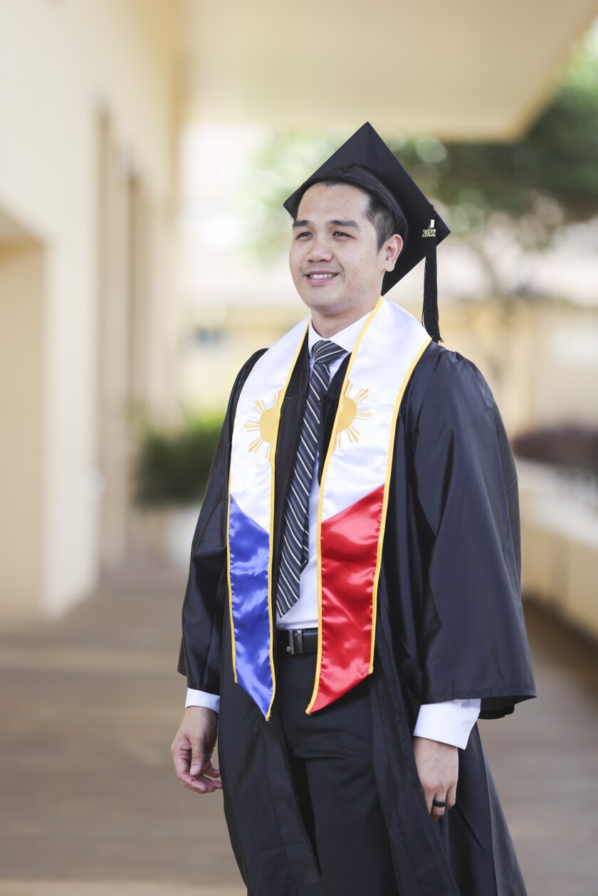 Micah wearing graduation cap and gown while standing outdoors.