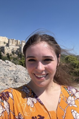 A girl takes a selfie in front of Greek ruins.