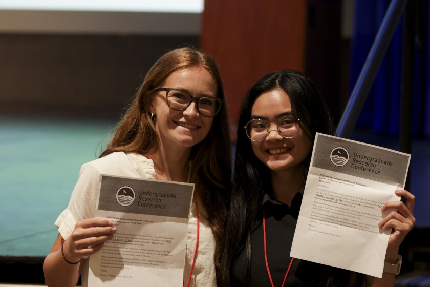 Jessika Santoso with her mentor, posing for a photo while holding a piece of paper featuring URC