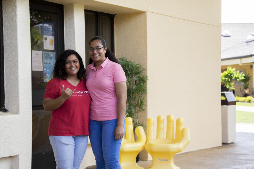 Two employees standing in front of the Alumni & Career Services' Office at the Canon Activities Center