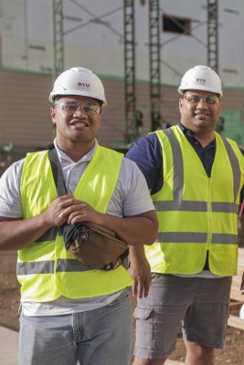 BYUH students at a construction site wearing neon vests and hard hats.