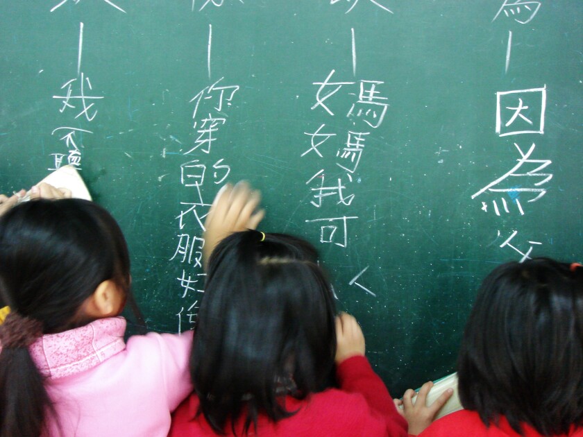 Children writing Chinese on a chalkboard.