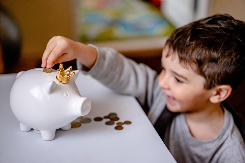 child putting money into a piggy bank