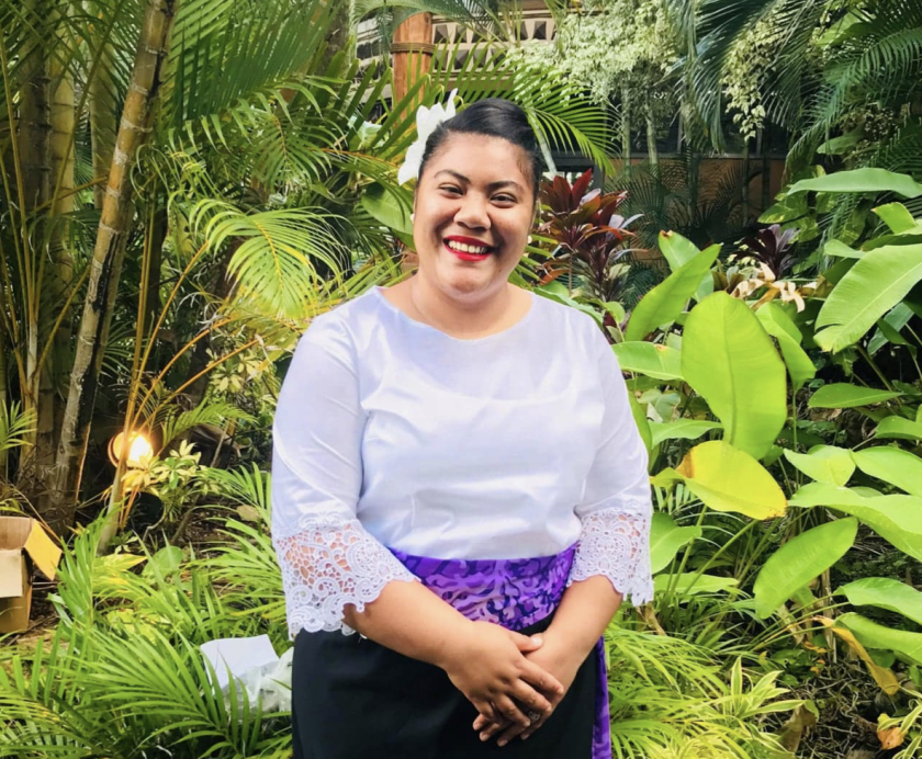 Sosefina Finau stands in front of foliage.
