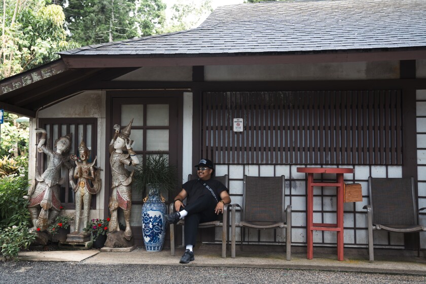 A man sits in front of a gift shop statues