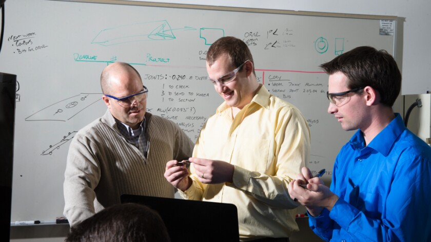 A professor mentoring several students in a lab environment