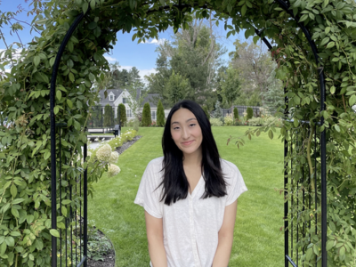 Gabbie Schwartz standing underneath an archway covered in foliage.