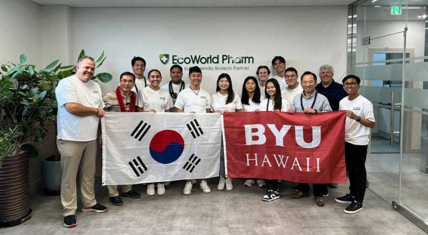 BYUH students and South Korean delegates holding a BYUH flag and a South Korean flag, respectively, in EcoWorld Pharm