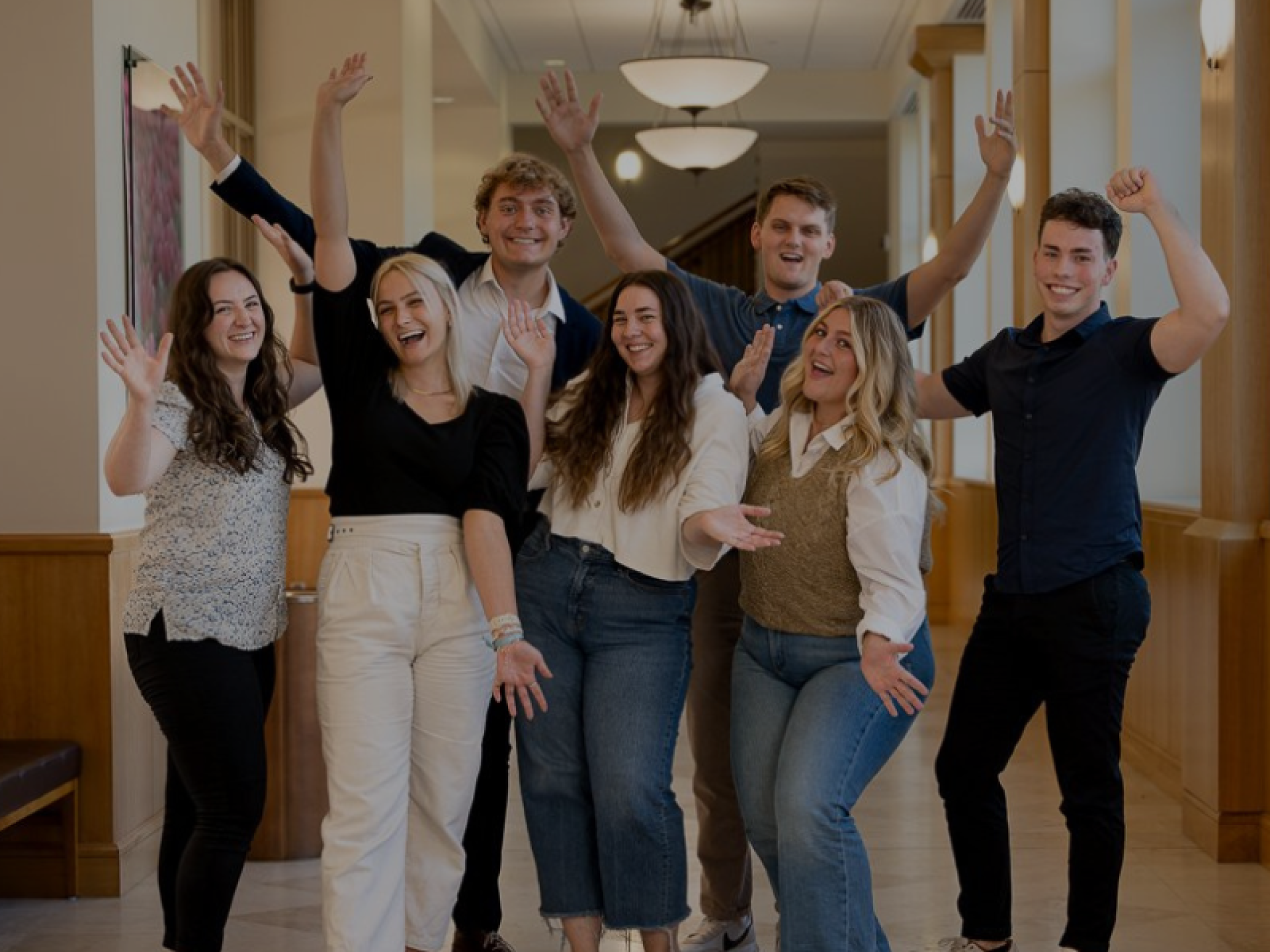 BYU Students, Group of smiling BYU Ballard Center student employees posing and celebrating in a bright campus hallway, showcasing teamwork, student leadership, and social impact involvement.