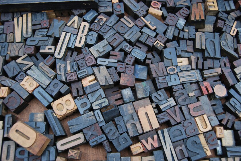 A collection of blue and beige letter stamps are displayed in a jumbled fashion on a table.