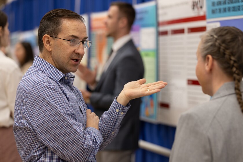 A professor speaks to a student presenter at the Mary Lou Fulton Mentored Student Research Conference. Along with guests, faculty members visited each poster and asked questions. (Photo courtesy of FHSS Media Team)