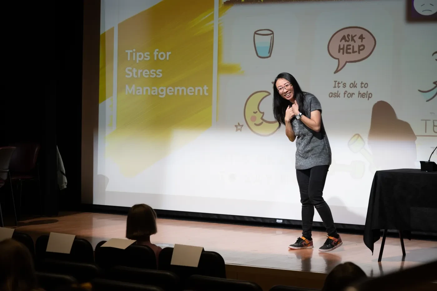 A professor smiles as she presents a slide entitled, "Tips for Stress Management"