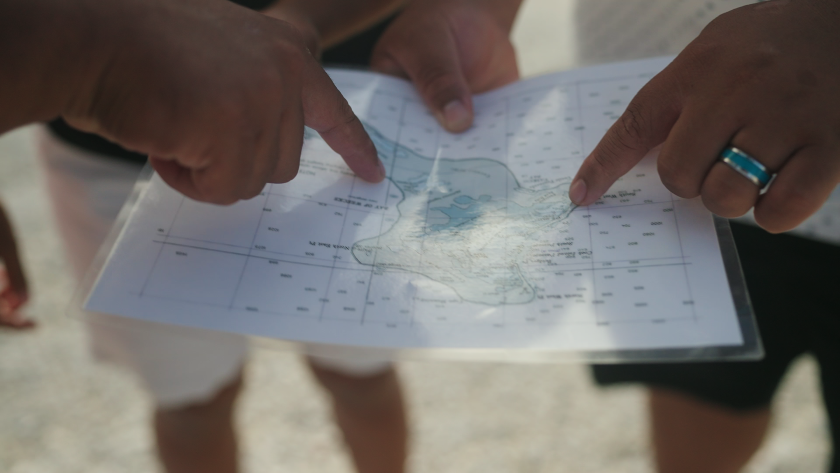 Fingers pointing toward a map of Christmas Island
