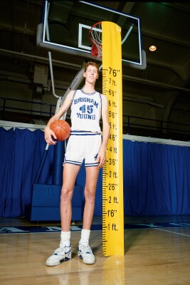 Shawn Bradley measuring 7'6" and holding a basketball