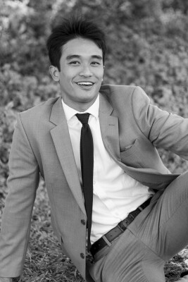 Black and White portrait of Meeprolam sitting on the ground smiling.