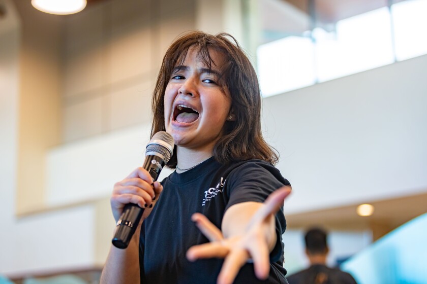 A woman holding a microphone sings passionately.
