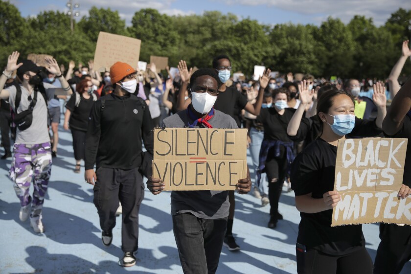 Protestors carry signs that read "Silence = violence" and "Black Lives Matter."