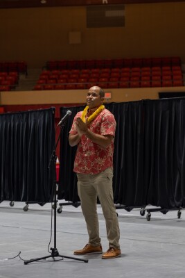 President Kauwe stands at the microphone on the floor of the CAC with his hands together in front of his chest