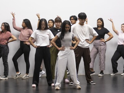 a group of young adults dancing on stage with a white background