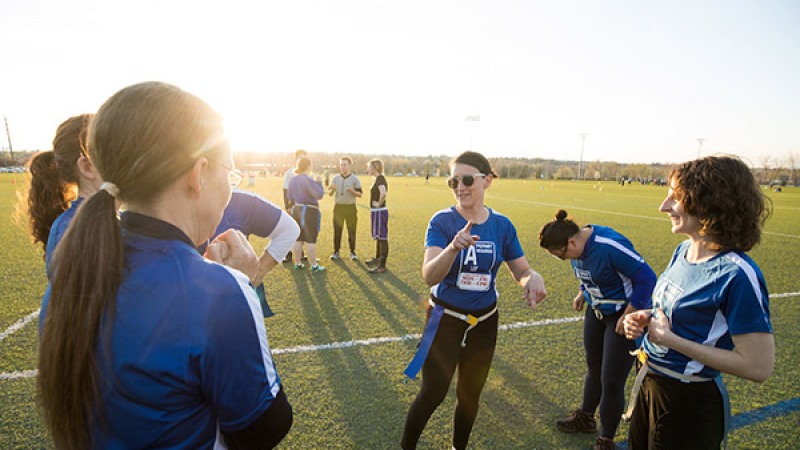 Three faculty members talk on the sideline during their flag football game