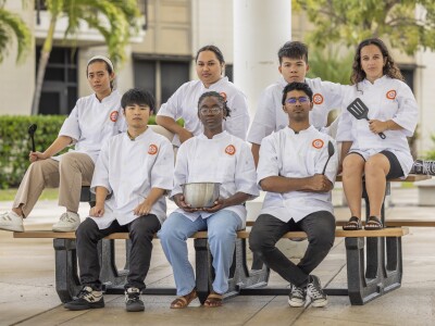 7 people wearing chef outfits holding cooking ware.