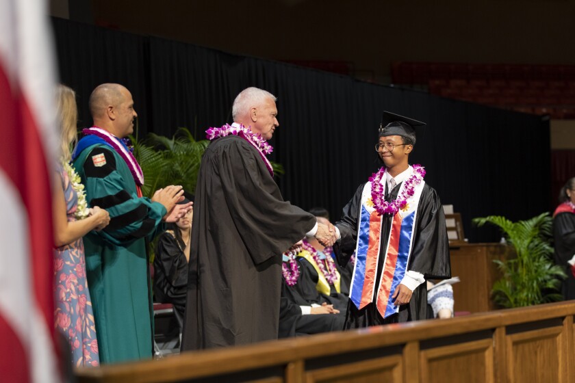 Two individuals shaking hands on Commencement Ceremony stage at a BYUH graduation.