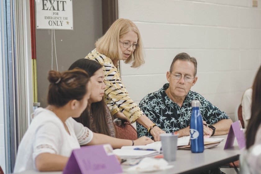 Carol Bennett instructs her husband Gary and 2 other students in a classroom