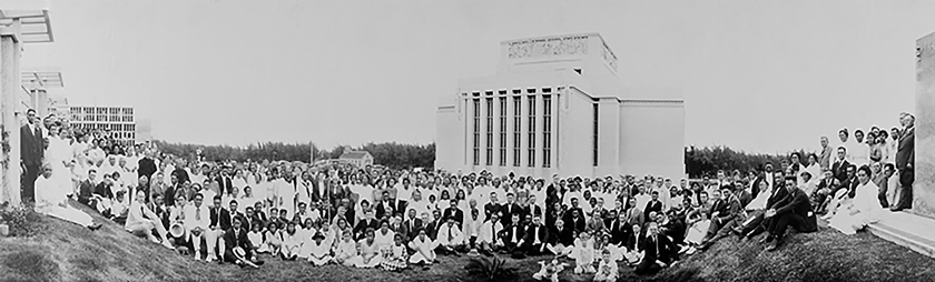 A historic black and white photograph of a large crowd of people in front of an ornate building.