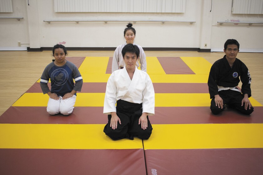 Four members of the Fūrinkazan Aikidō Dojo sit on a mat in the Dance Studio on campus