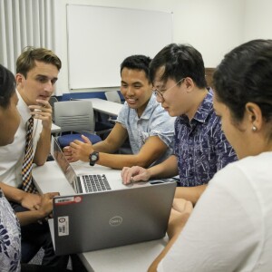 students gathering together using laptops
