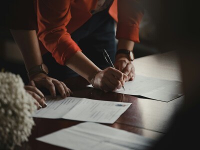 A person holding pen and signing a document