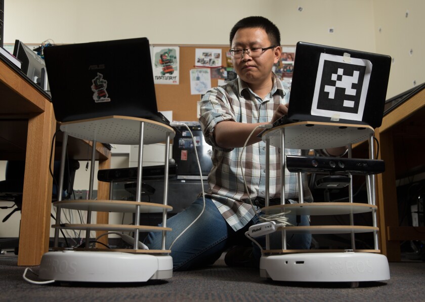 Computer Science student Daqing Yi programs robots in a lab.