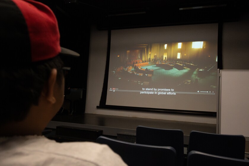A shot of a student watches a movie taken from his behind.