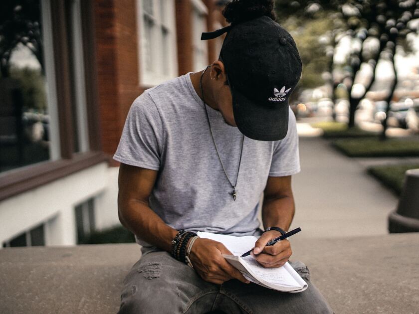 man sitting a writing in a notepad