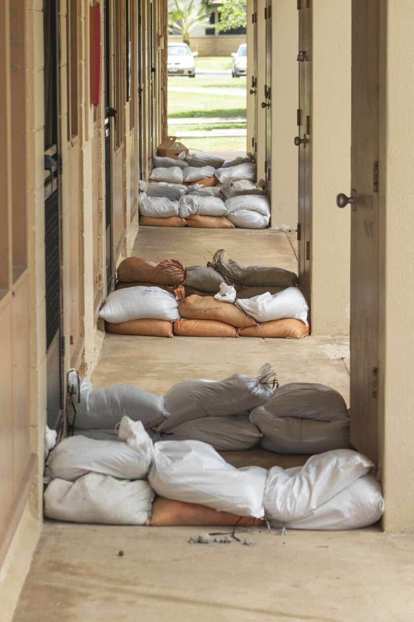 In an outdoor hallway sandbags are pilled up by doors at TVA.