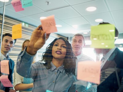 Image of a group of people sticking notes to a clear board.