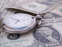 Pocket watch resting on dollar bills.