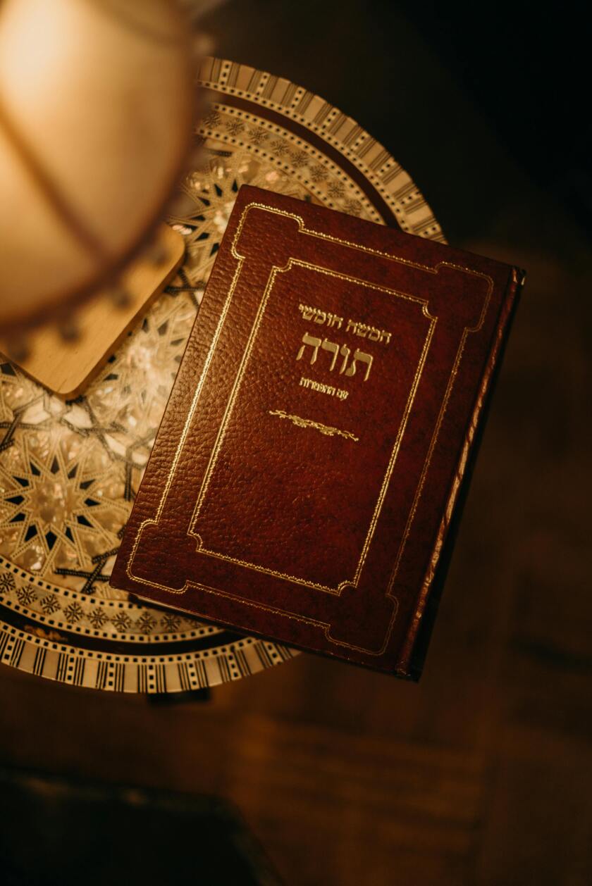 Hebrew Scriptures on a table under a lamp.