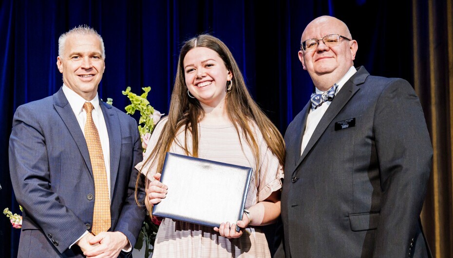 Student receiving award at past banquet, accompanied by President Kevin Worthen and three other individuals