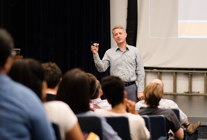 Political science professor Troy Smith stands in front of a crowd of seated people