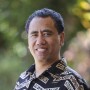 Moku Kaaloa's smiling headshot with outdoor blurred background.