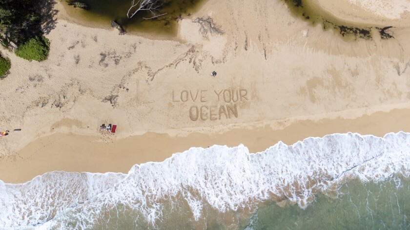 A drone shot of a beach in Laie with the words "Love your ocean" drawn in the sand.