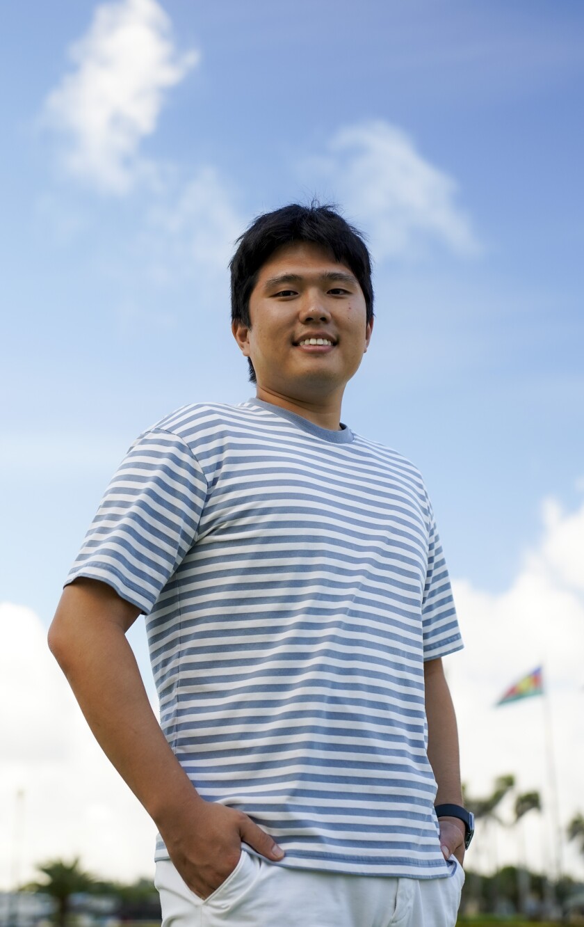 A guy in a blue and white striped shirt poses for the camera.