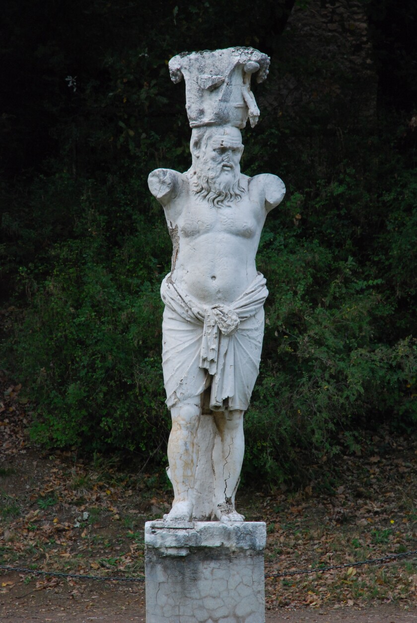 Statue of a man without arms standing on a short pillar.