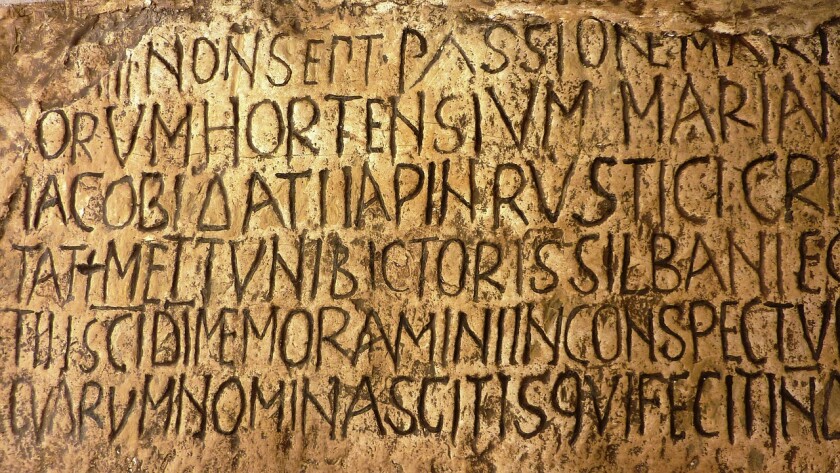 Latin engravings on a stone wall in the Vatican.